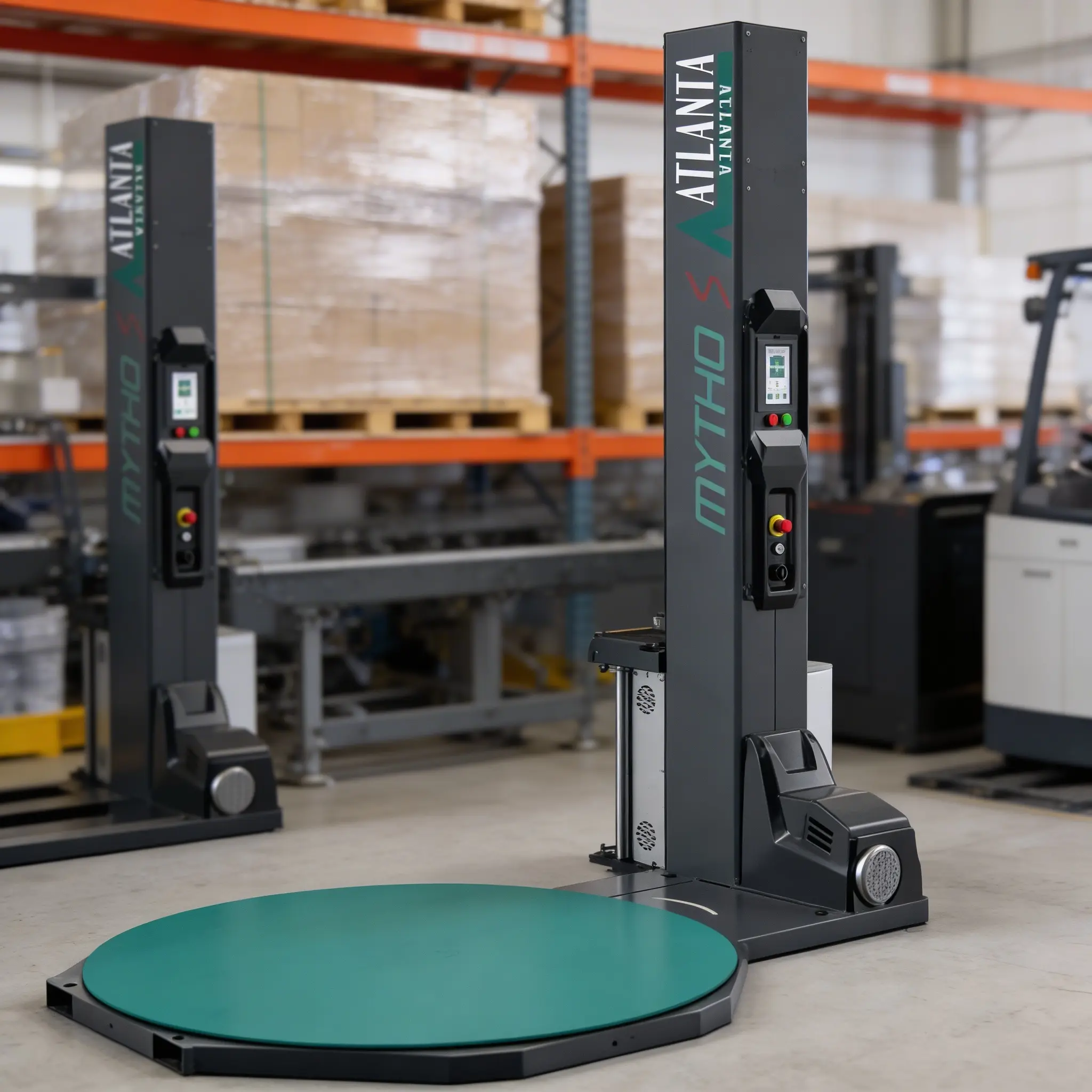 A pallet wrapping machine type MYTHO with a green turntable and upright control panel stands in a warehouse with shelves and boxes in the background.
